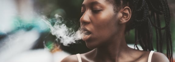 Young adult female glowing smoke out of her mouth.