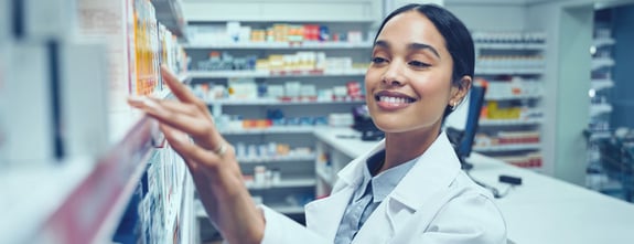 A female pharmacist looking for a medication on the shelf.