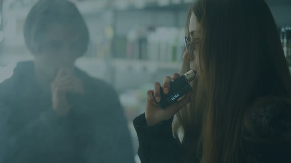 Teenage girl hitting a vape pen